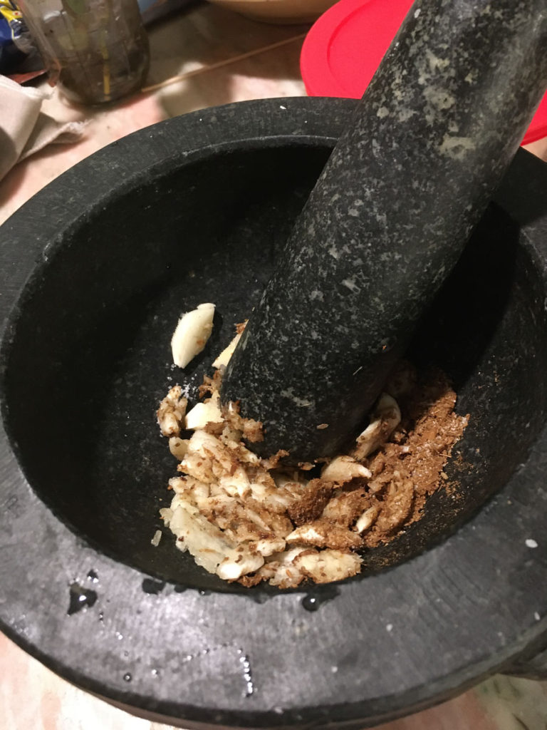 Mortar and pestle with crushed garlic and cumin.