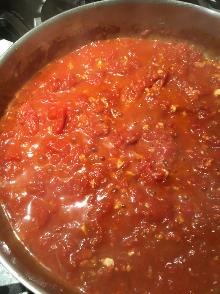 Tomato sauce bubbling in a silver pan.