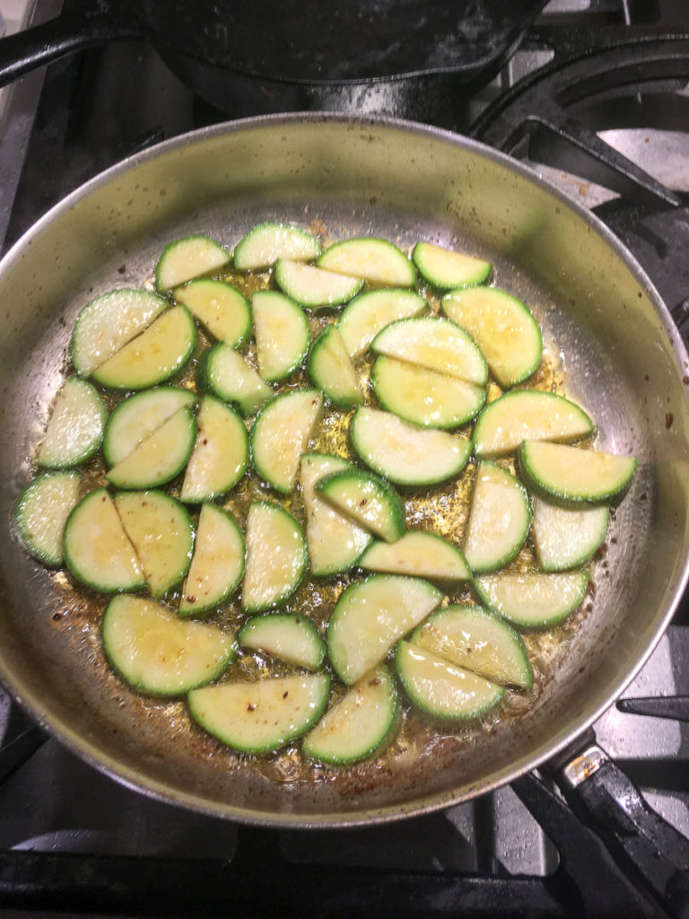 Half-round slices of squash in a skillet -- beautiful green edge, turning to yellow and white on each slice